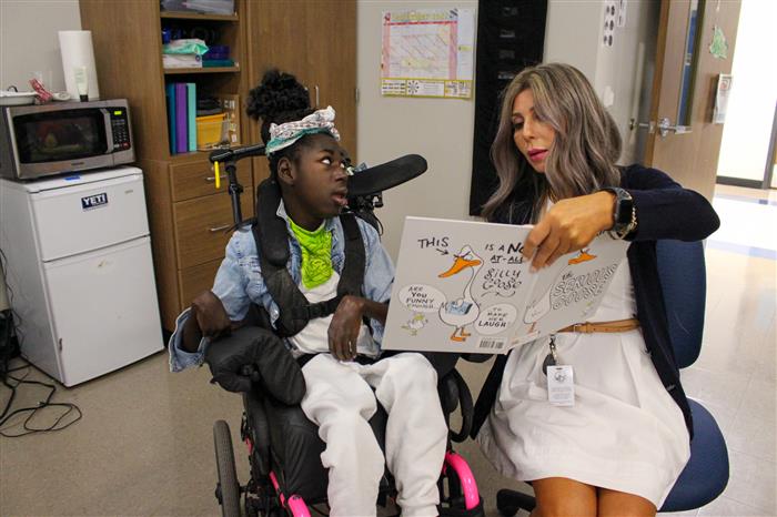 Teacher reading to a disabled student